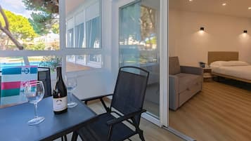 Une chambre à coucher moderne avec un lit, une petite table sur laquelle se trouvent une bouteille et un verre, et une chaise.
