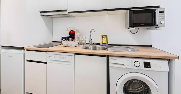 A compact kitchen with a sink, microwave, dishwasher, and washing machine.