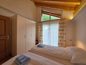 Ein Schlafzimmer mit einem Bett, einem Kleiderschrank und einem Fenster mit Vorhängen.