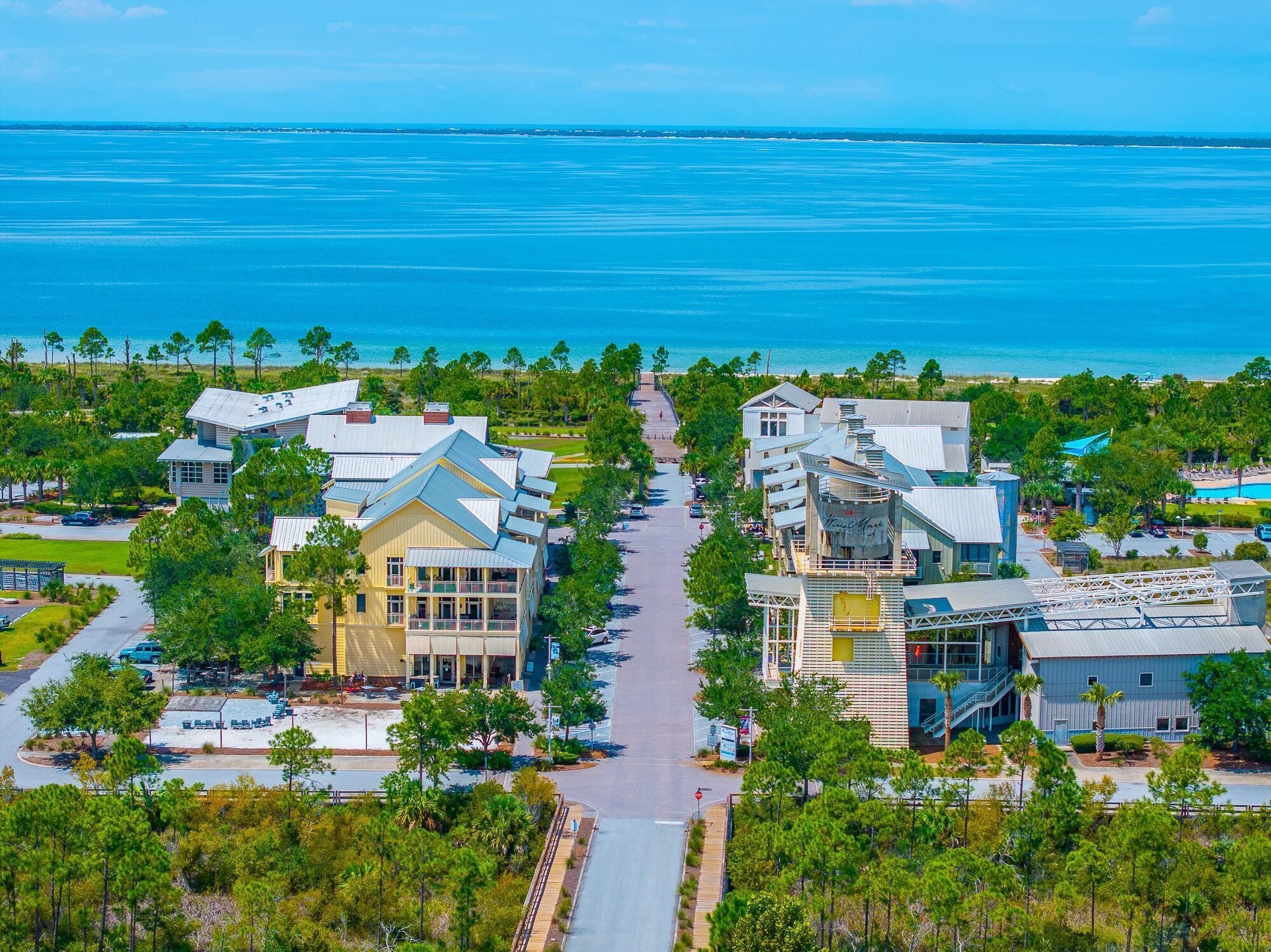 A coastal resort with multiple buildings, a central walkway, and a view of the ocean.