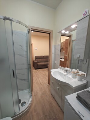 Un bagno moderno con box doccia in vetro, un ampio lavandino con specchio e pavimento in legno.