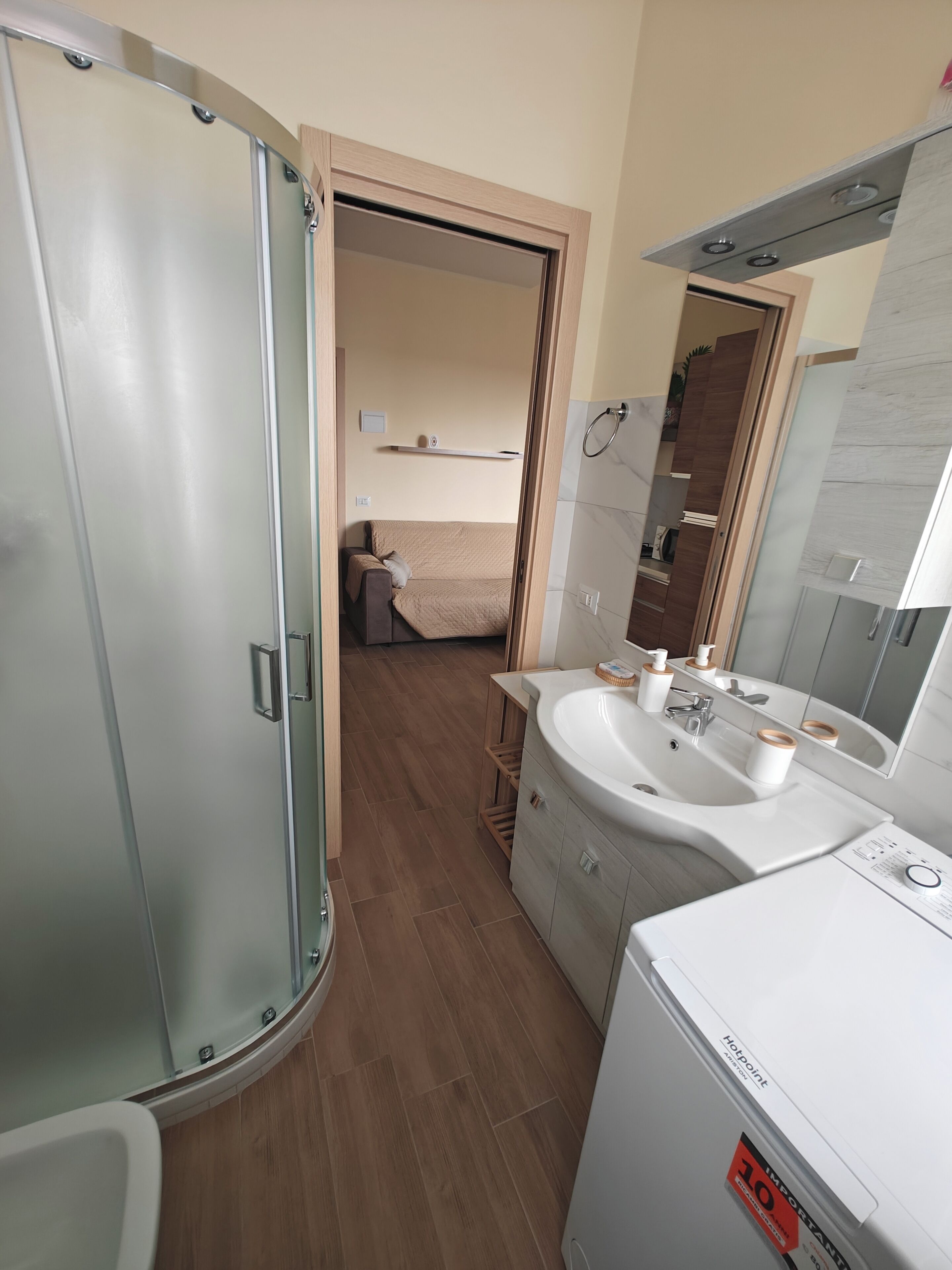 Un bagno moderno con box doccia in vetro, lavandino con specchio e servizi igienici.