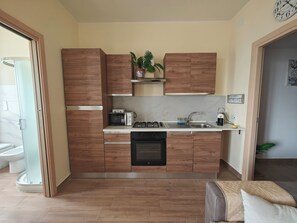 Una cucina moderna con mobili in legno, forno integrato, microonde e piano cottura a gas.