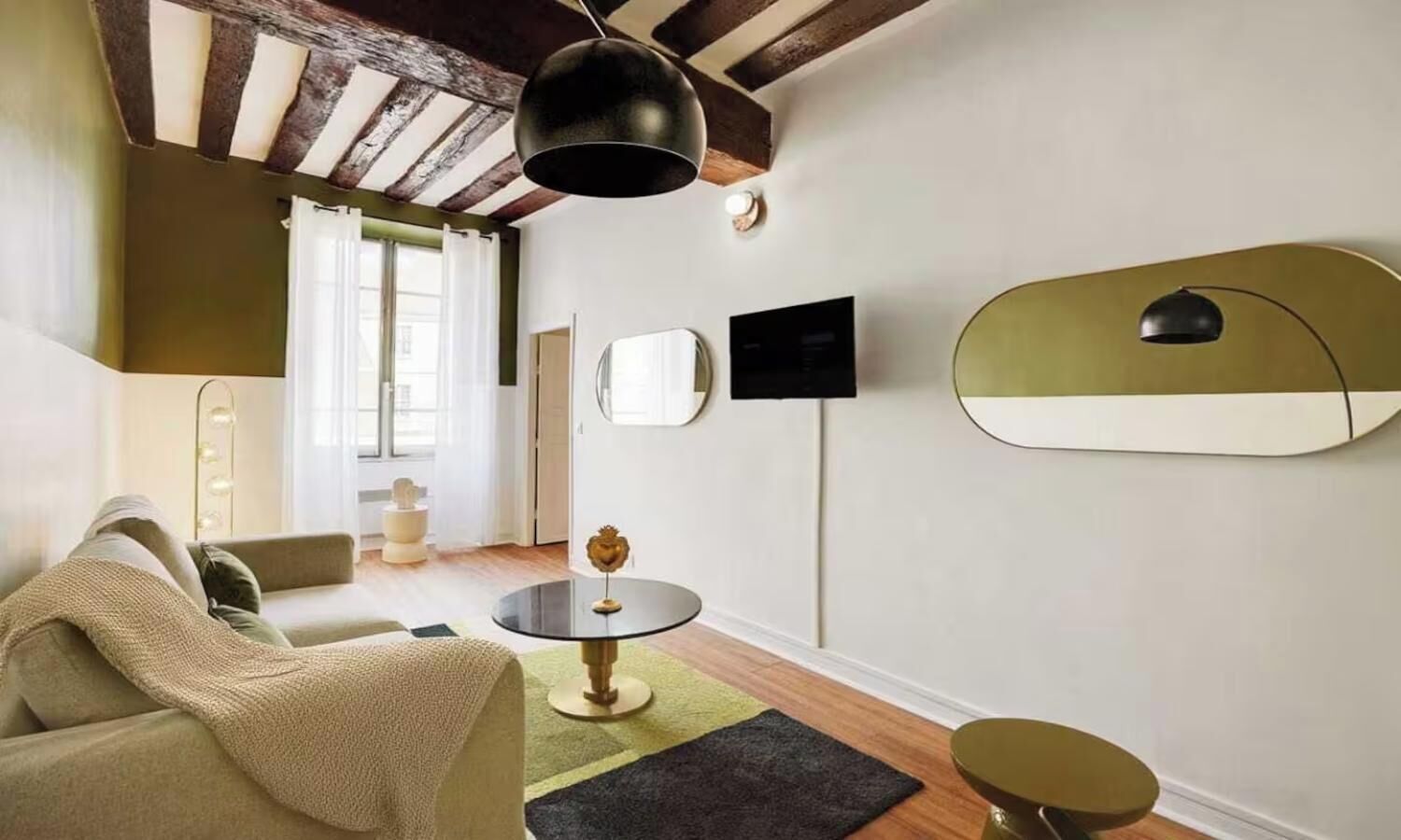 Una sala de estar moderna con un sofá, una mesita redonda y un televisor montado en la pared.
