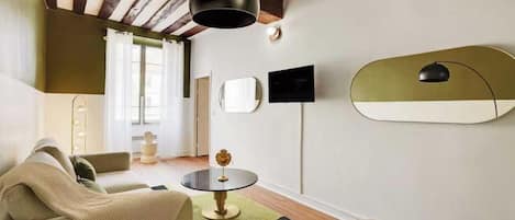 A modern living room with a sofa, a round coffee table, and a television mounted on the wall.