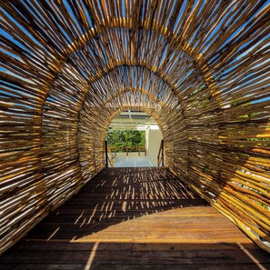 An arched wooden structure with a wooden floor leading to a building entrance. - 10-bedroom- all Suites - Wellness Compound - Private Sauna/Ice Bath/Yoga Deck (Tulum)