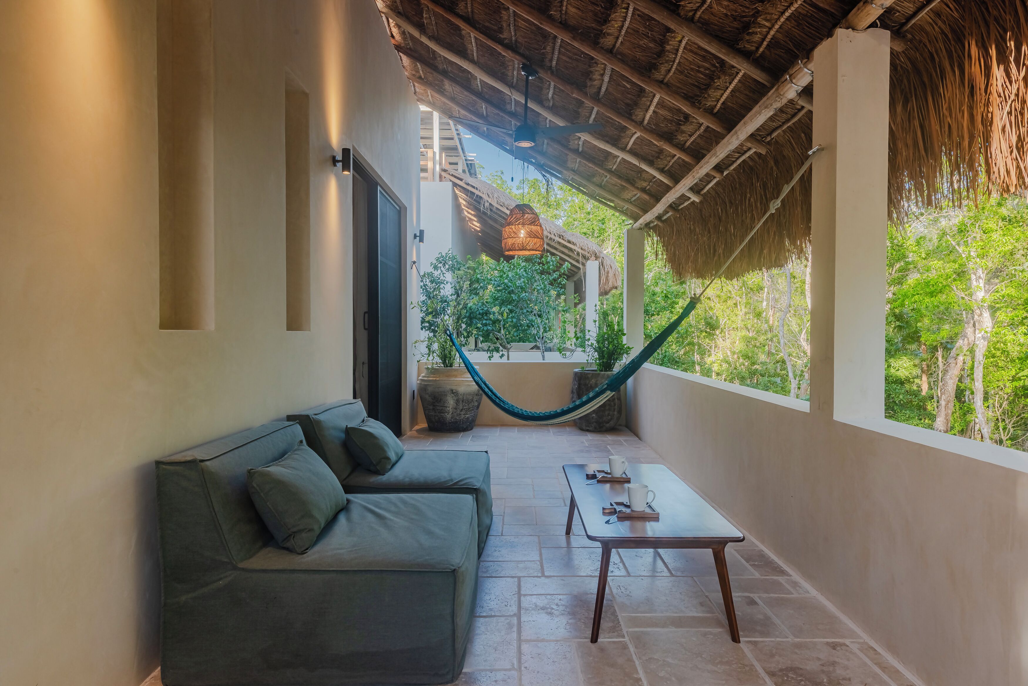 A covered outdoor seating area with a sofa, a table, and a hammock.