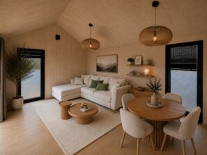 A modern living room with a sectional sofa, a round wooden dining table with chairs, a coffee table, and two hanging wicker lamps. - Chalet Scandi – Sauna & Mountain Views Near Kufstein (Ebbs)