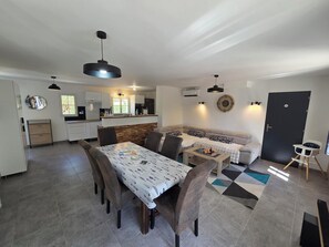 A modern kitchen with a dining area, a sofa, and a baby chair. - Vrbo Property (La Jonchère)