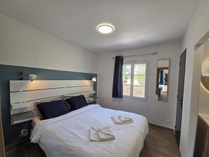 A bedroom with a bed, bedside tables, a nightstand, a window with curtains, and a mirror. - Vrbo Property (La Jonchère)