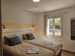 A bedroom with two beds, a window with curtains, and a ceiling light. - La Brunette Océane - An air-conditioned retreat in the Vendée, 15 minutes from the beaches (La Jonchère)
