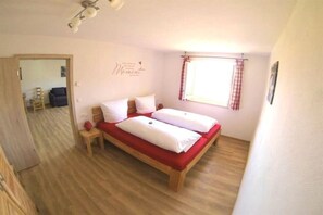 A bedroom with a double bed, a bedside table, a window with curtains, and a wall decoration. - Country House Dream View (Ofterschwang)