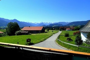 A rural road leading to a village with houses and a mountain range in the background. - Country House Dream View (Ofterschwang)
