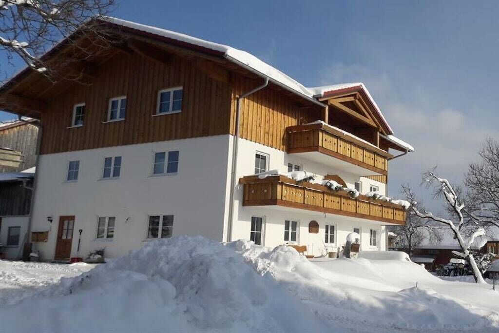 A multi-story building with a wooden facade and balconies, surrounded by snow.