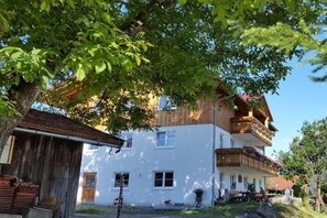 A two-story building with balconies, a wooden structure to the left, and a clear sky. - Country House Dream View (Ofterschwang)