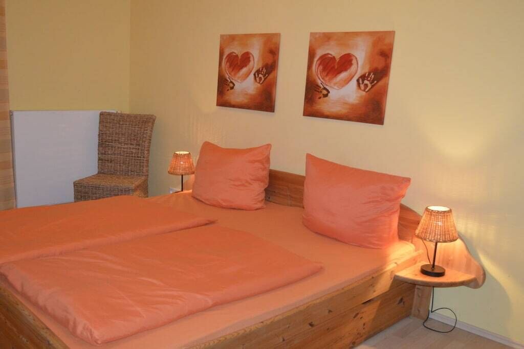 Ein Schlafzimmer mit einem hölzernen Bett, zwei Kissen, einer Nachttischlampe und zwei Wandbildern.