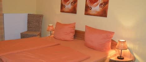Ein Schlafzimmer mit einem hölzernen Bett, zwei Kissen, einer Nachttischlampe und zwei Wandbildern.