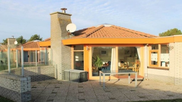 Uma casa moderna com varanda, chaminé e antena parabólica.