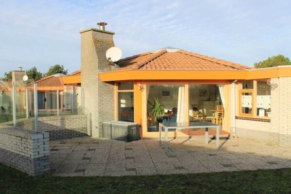 A modern house with a patio, a chimney, and a satellite dish. - Bungalow with 2 bedrooms (Julianadorp aan zee)