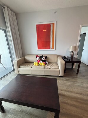 A living room with a beige sofa, a dark coffee table, a lamp, and a large abstract painting on the wall. - Charming 2-bedroom apartment at MELIA
CELEBRATION 
No resort fee
Free Shuttle  (Kissimmee)