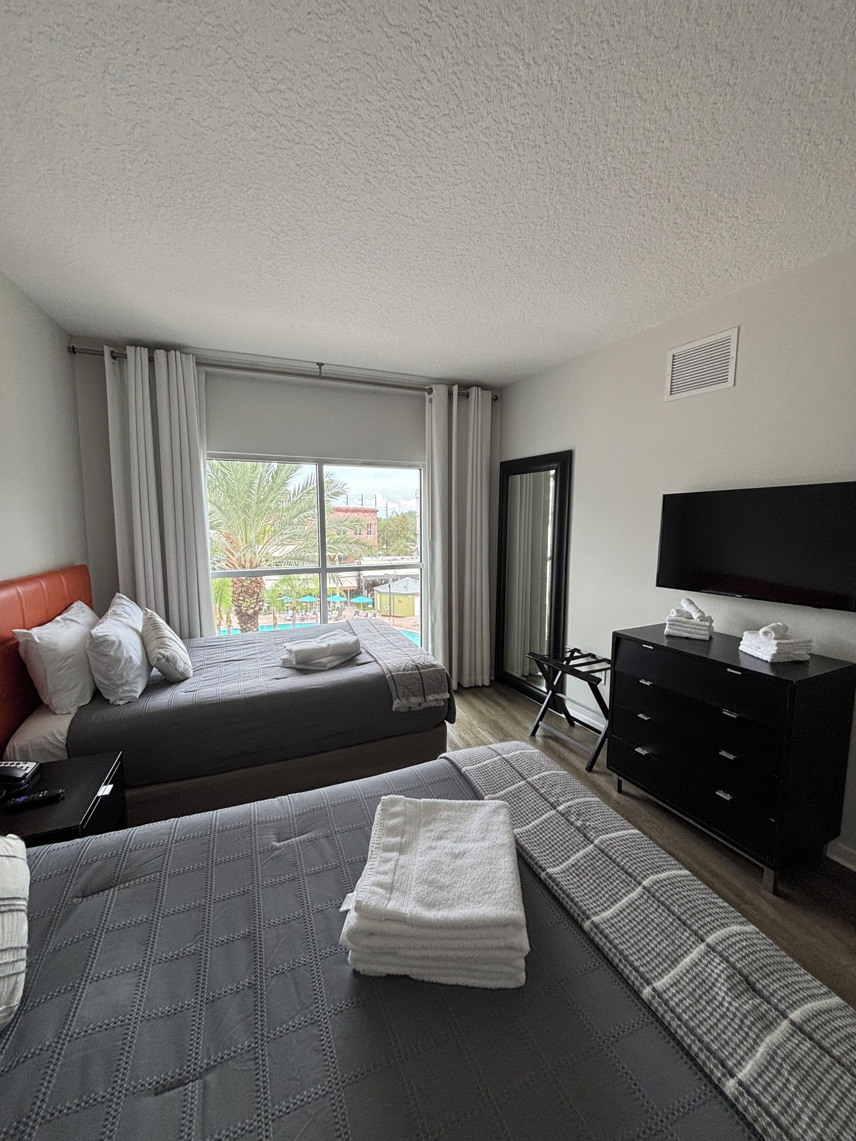 Habitación de hotel con dos camas, televisión, escritorio y vistas al exterior.