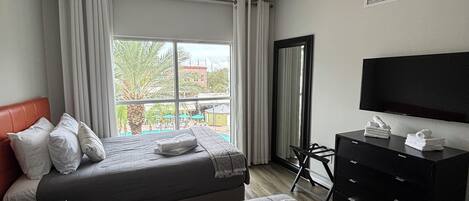 Habitación de hotel con dos camas, televisión, escritorio y vistas al exterior.