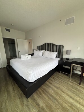 A hotel room with a large bed, a bedside table, a desk, and a door. - Charming 2-bedroom apartment at MELIA
CELEBRATION 
No resort fee
Free Shuttle  (Kissimmee)
