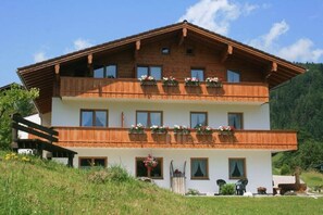Eine zweistöckige Holzhütte mit Balkonen, einer Veranda und einem Blick auf die Berge.
