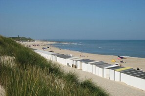 Ein Strand mit weißen Strandhütten, sandigem Ufer und blauem Himmel.