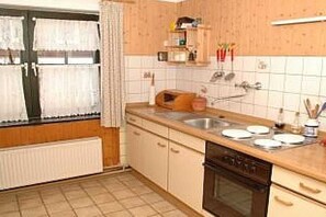 Et køkken med komfur, vask og skabe.