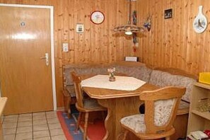 A wooden-paneled room with a dining table, chairs, a bench, and a door. - Holiday apartment with 1 bedroom (Braunlage)
