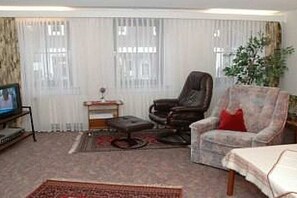 A living room with a television, a sofa, an armchair, and a small table with a plant. - Holiday apartment with 1 bedroom (Braunlage)