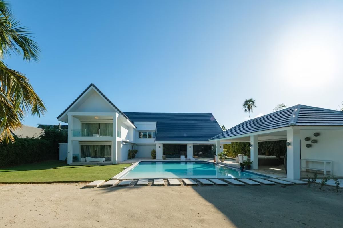 A modern two-story house with a swimming pool, a covered patio, and a well-maintained lawn.