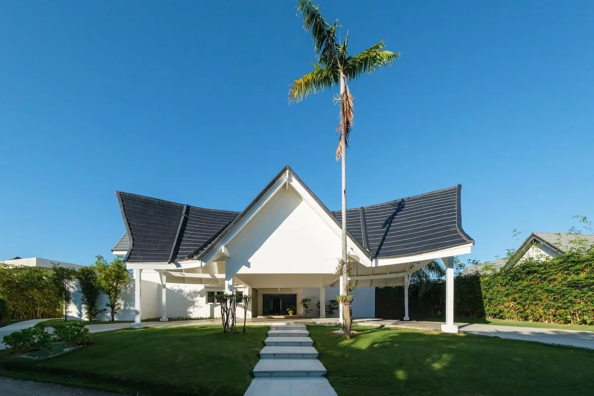 Uma casa moderna de dois andares, com varanda coberta, entrada central e gramado bem cuidado.