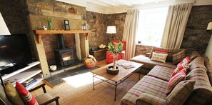 Ein gemütliches Wohnzimmer mit Kamin, Fernseher, Sofa und Couchtisch.