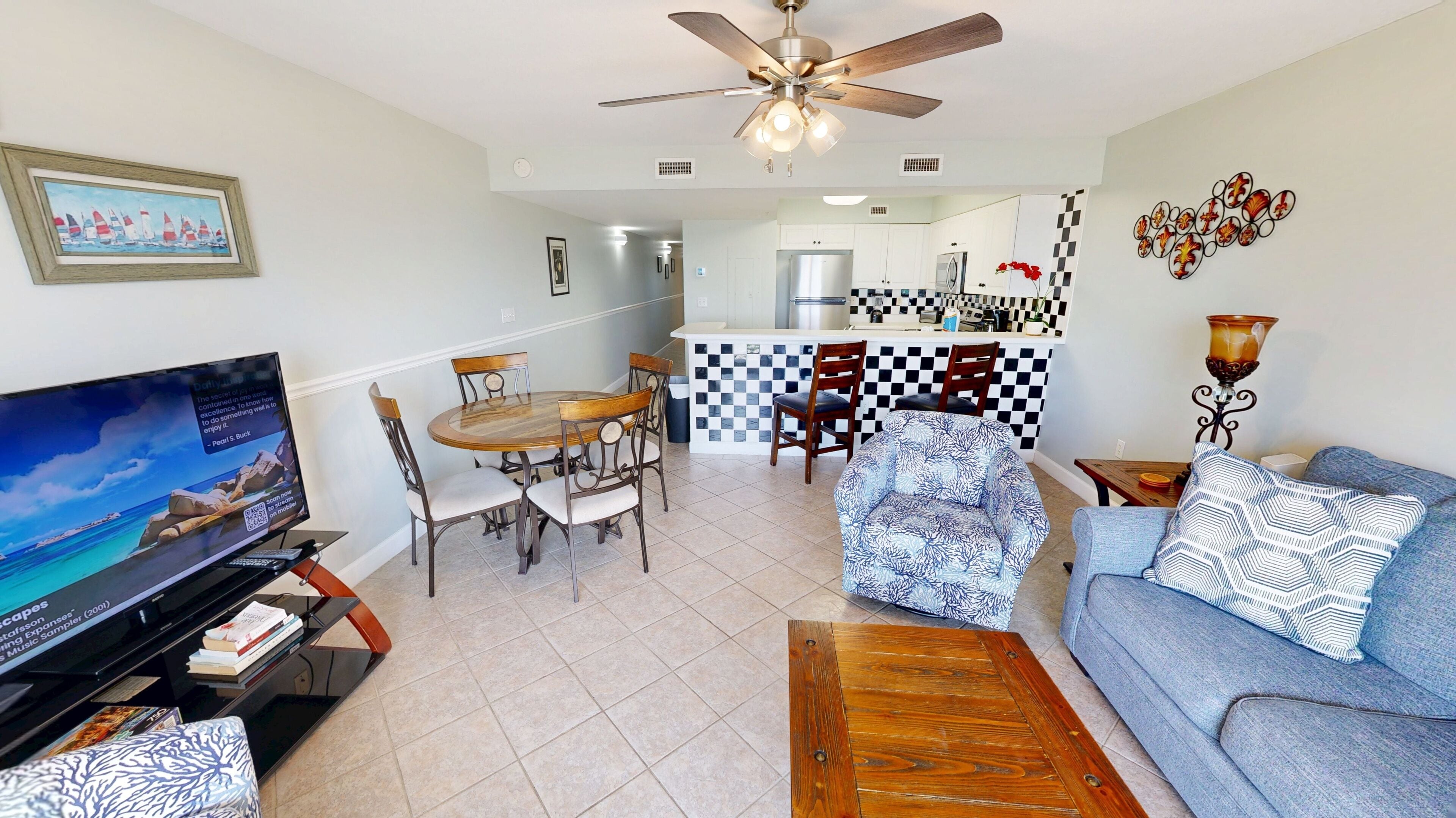 A living room with a television, a sofa, a coffee table, and a dining area with chairs and a table.