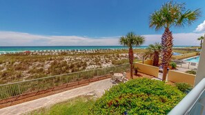 Un balcon avec vue sur la plage, les palmiers et une piscine.