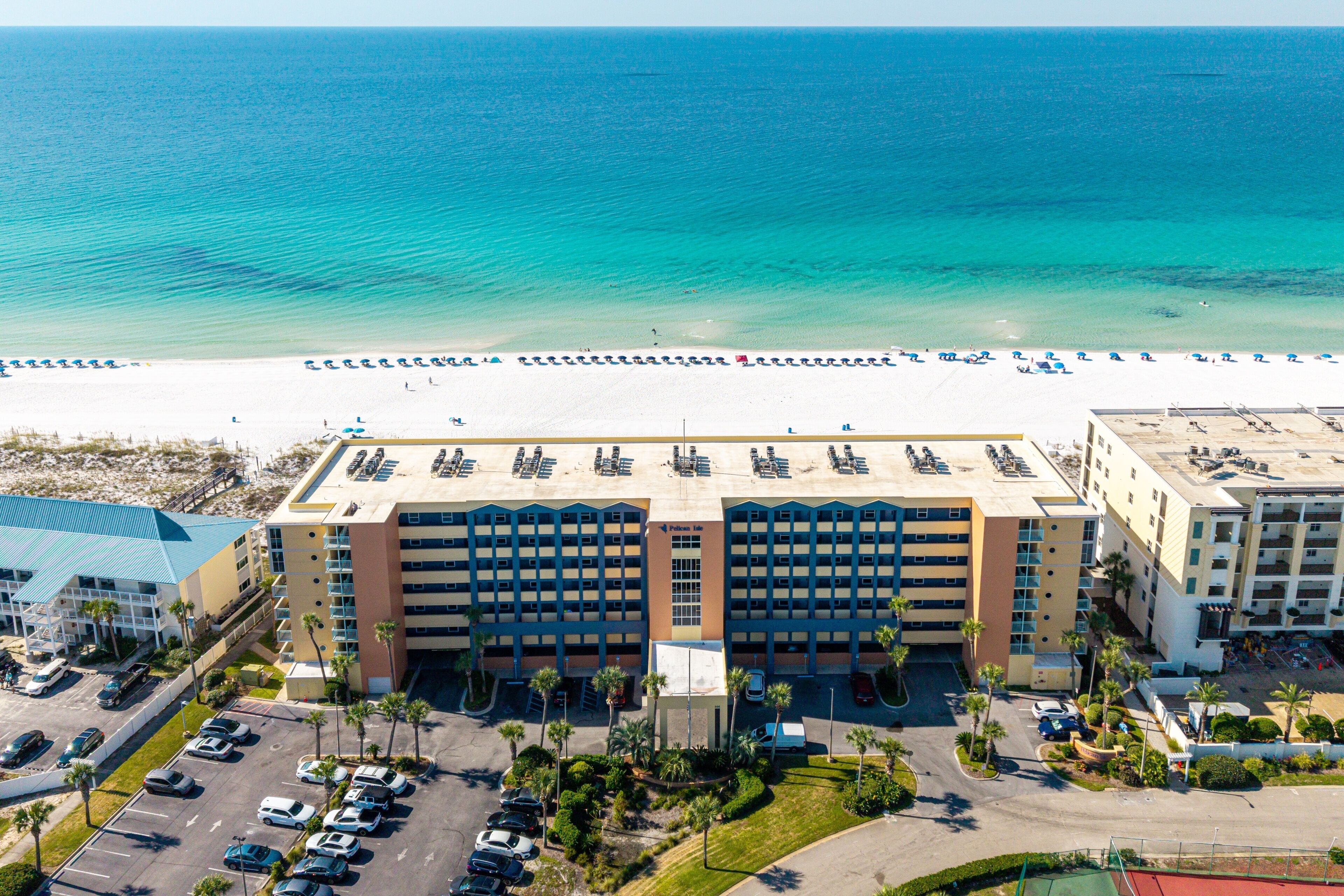 A hotel with a central courtyard, parking area, and a beach view.