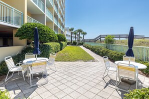 Eine Hotelterrasse mit Außenplätzen, einem kleinen Rasen und Blick auf das Meer.