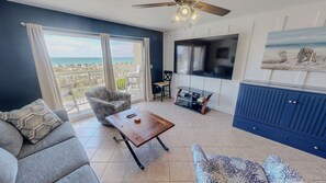 Ein Wohnzimmer mit einer Couch, einem Couchtisch, einem Fernseher und Blick auf den Ozean.