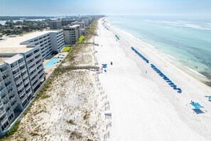 A beachfront hotel with multiple floors, a pool, and beach umbrellas. - Islander Beach Resort 0607 1 Bedroom Condo (Fort Walton Beach)