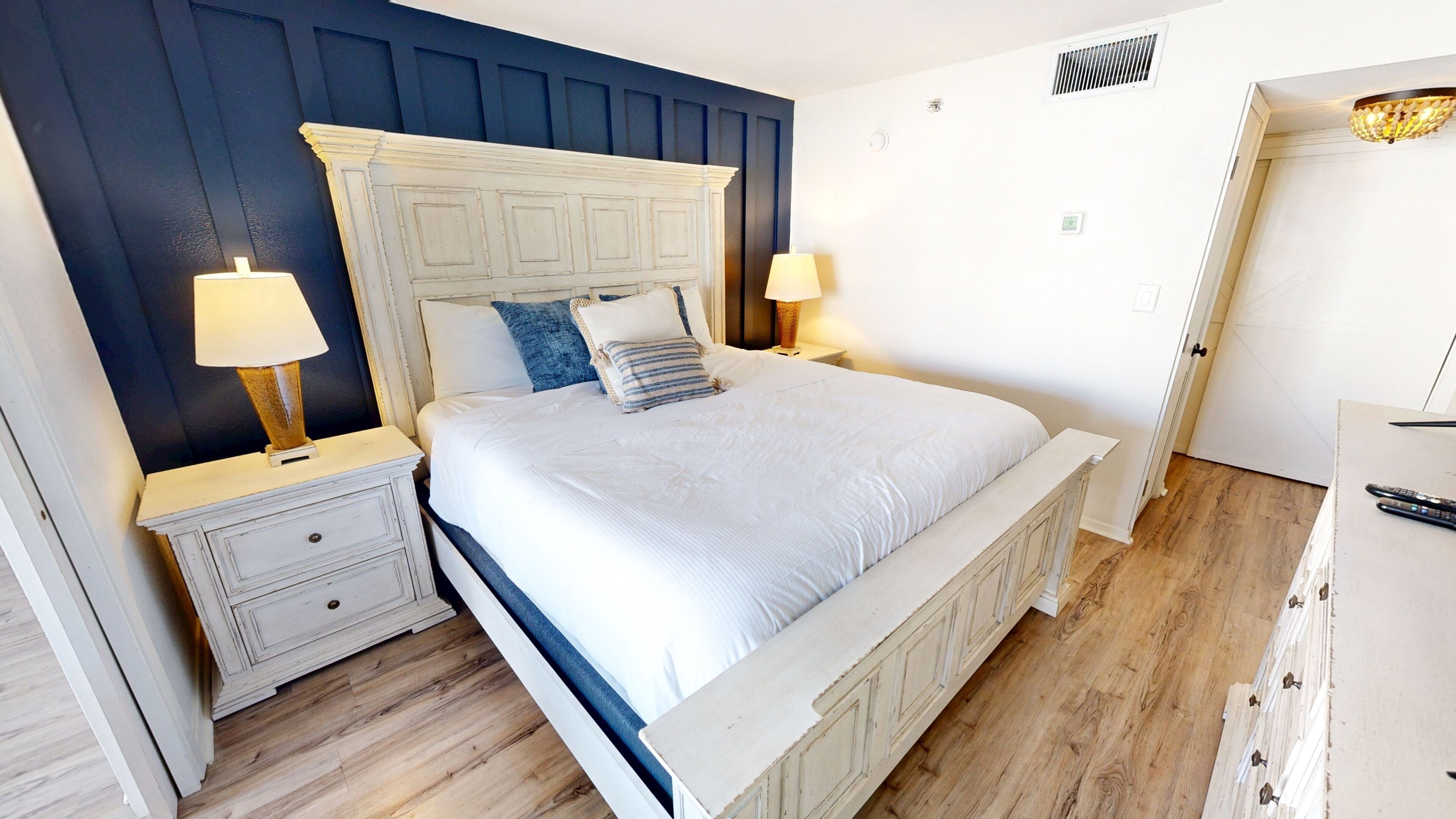 A bedroom with a bed, nightstands, lamps, and a dresser.