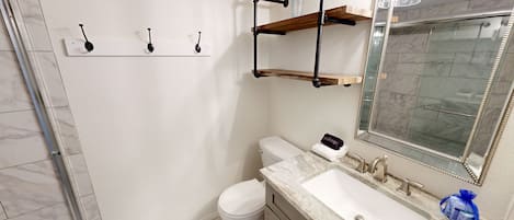 A bathroom with a toilet, sink, mirror, and towel rack.