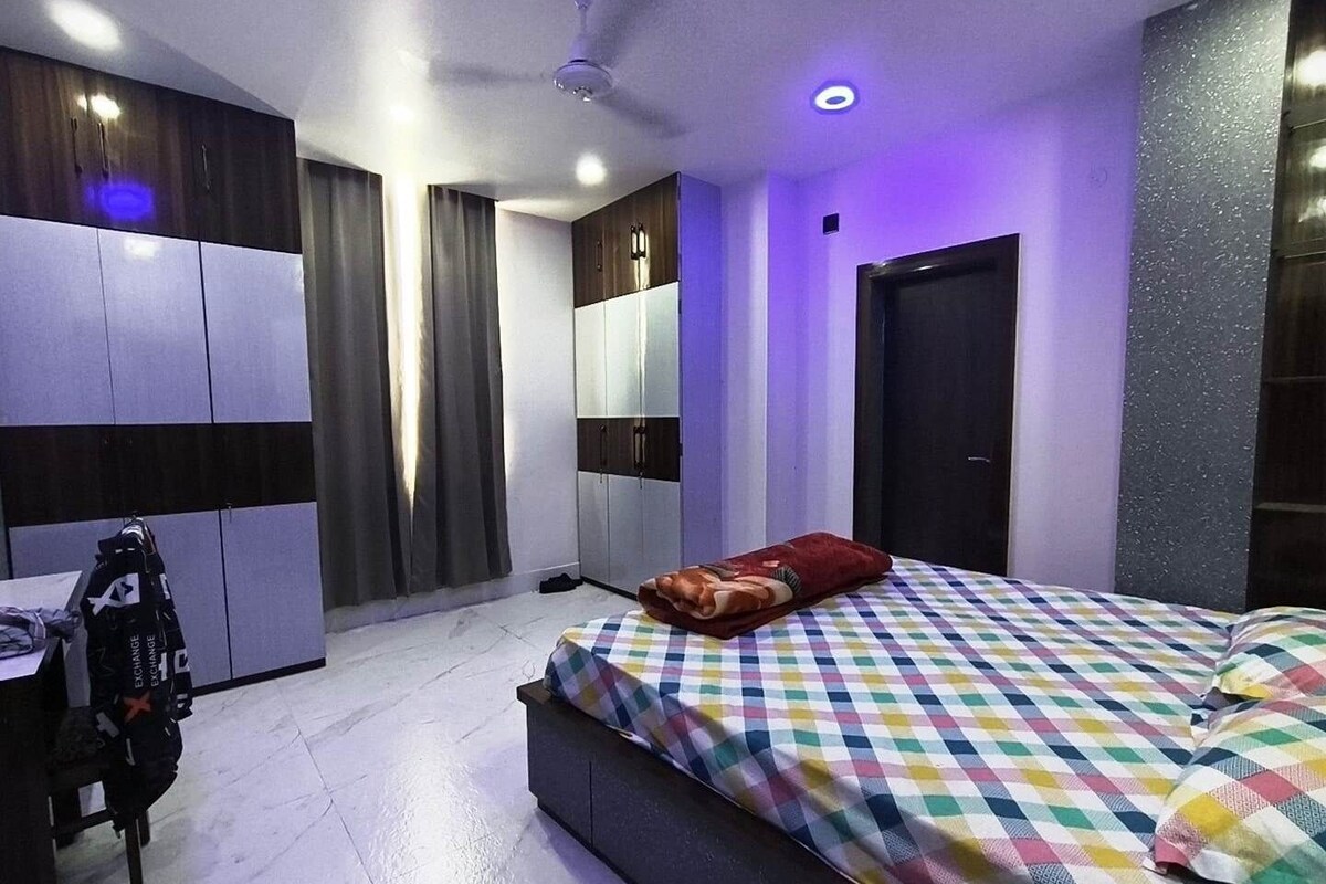 A modern bedroom with a bed, a desk, and a wardrobe.