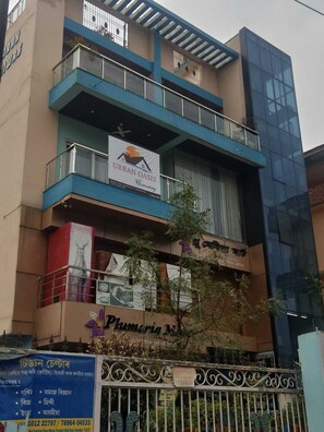 A multi-story building with a sign for 'Urban Oasis Homestay' and a visible storefront named 'Plumeria M.'