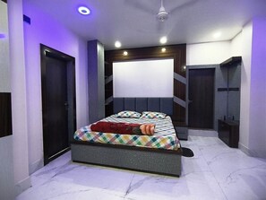 A bedroom with a bed, a headboard, a door, and a ceiling light. - Urban Oasis (Guwahati)