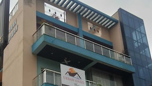 Ein mehrstöckiges Gebäude, im zweiten Stock ein Schild mit der Aufschrift 'Urban Oasis Homestay'.