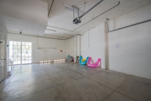 A spacious room with a large open area, a door with a view to the outside, and a projector mounted on the ceiling. - 1415 Gulf Dr N Holmes Beach, Anna Maria Island 3 Bedroom Townhouse (Bradenton Beach)
