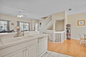 A kitchen with a white countertop, a sink, and a staircase leading to an upper level. - 1415 Gulf Dr N Holmes Beach, Anna Maria Island 3 Bedroom Townhouse (Bradenton Beach)
