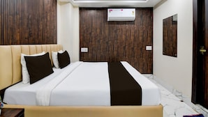 A modern hotel room with a large bed, wooden panel walls, an air conditioning unit, and a marble floor. - Classic With View Mivaan Comfort (Barasat)